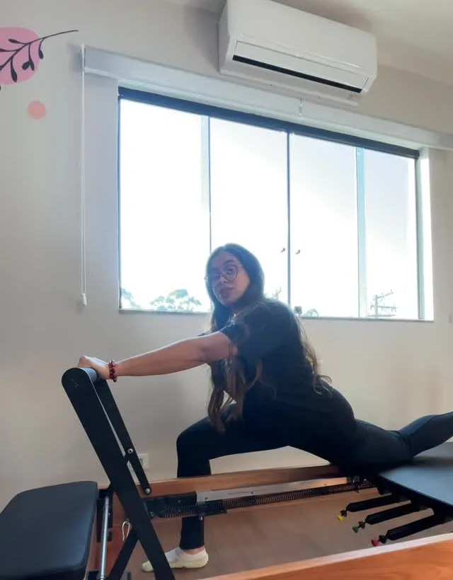 Alongamento de pernas em um aparelho do studio, com a mão apoiada na barra